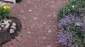 A brick pathway leading to a house with a porch, surrounded by various plants and flowers. - No hidden cleaning charges.  Huge 3bd/3ba apartment with tons of waterviews. (Belfast)