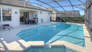 Et overdækket swimmingpool med terrasse, stole og et bord.