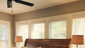 Une chambre à coucher avec un lit en bois, deux lampes de chevet et un ventilateur de plafond.