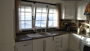 Een keuken met een groot raam, een spoelbak en kasten.