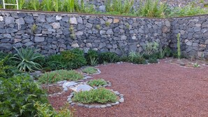 A garden with a stone wall, various plants, and a gravel path. - Casa Julietta - comfortable and spacious home with the BEST VIEWS in La Gomera (Hermigua)