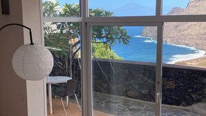 A room with a large glass door leading to a balcony with a view of the ocean and rocky cliffs. - Casa Julietta - comfortable and spacious home with the BEST VIEWS in La Gomera (Hermigua)