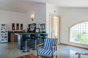 Enjoy meals in this kitchen with a central island and bar stools, surrounded by a view of lush greenery.