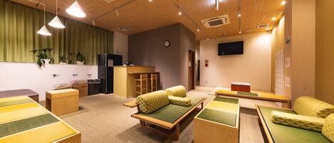 A room with multiple tatami mat beds, a reception desk, and a clock on the wall.