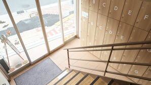 A staircase leading to a wooden locker area with alphabet labels. - bnb+ Tsuruhashi - Hostel (Osaka)