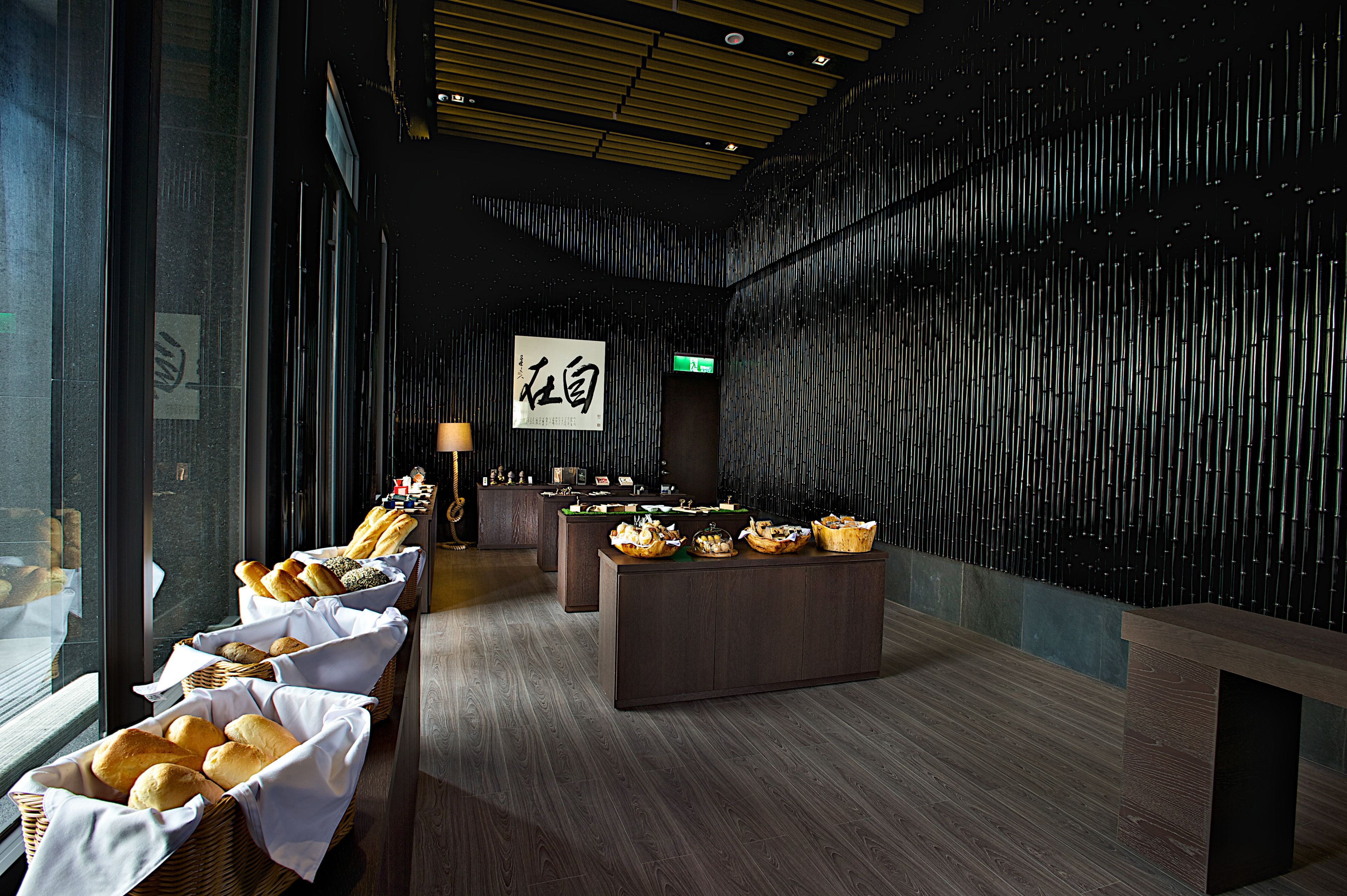 A modern interior with a reception desk, baskets of bread, and a wall with vertical lines.