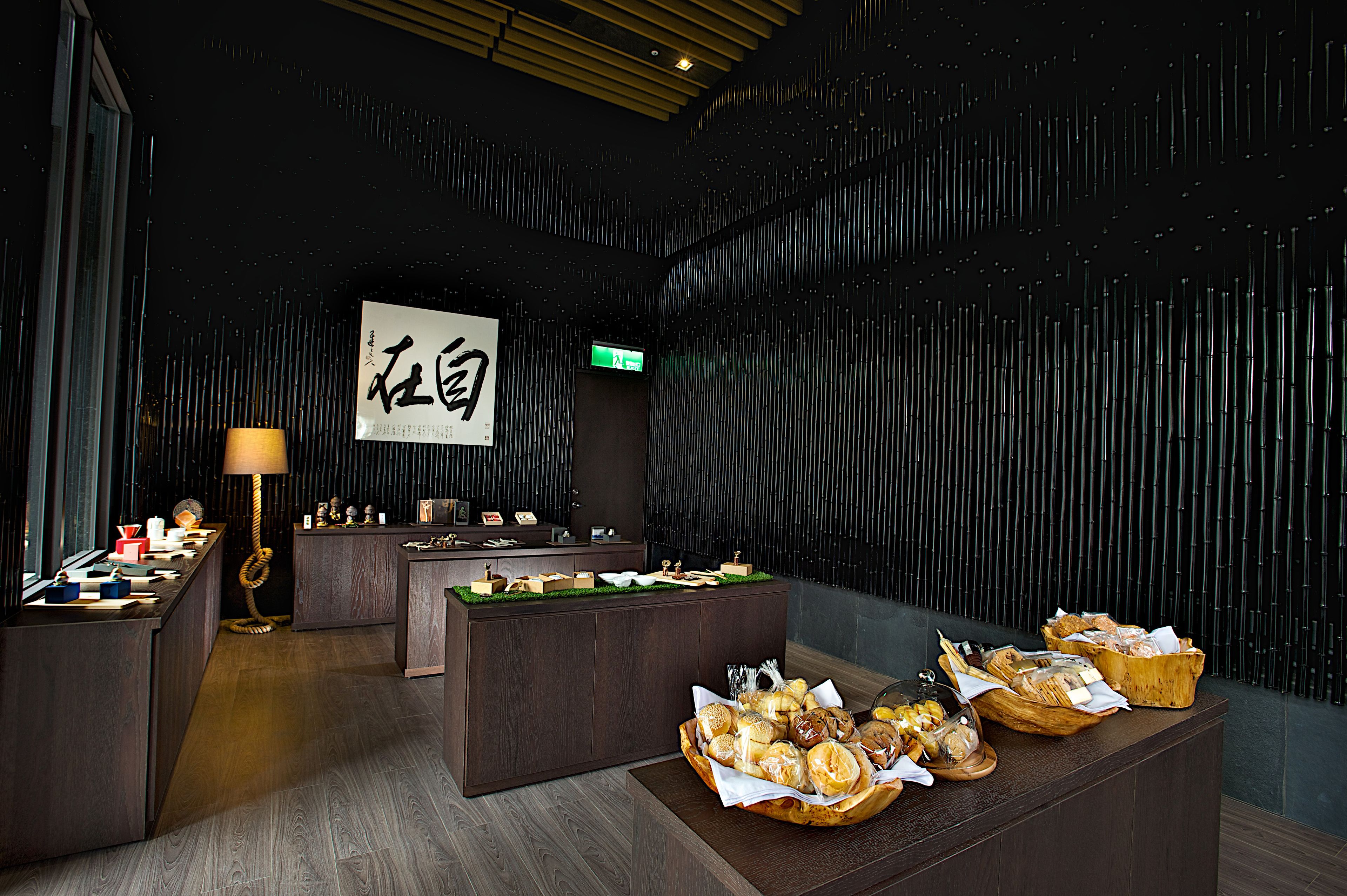 A reception area with a dark wooden reception desk, a wall-mounted sign, and a buffet table with various baked goods.