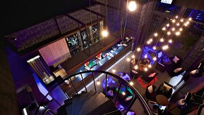 A bar area with a counter, seating, and hanging lights.