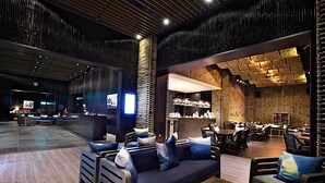 A modern lounge area with seating arrangements, a reception desk, and a bar area.