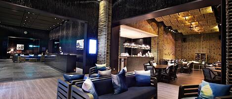 A modern lounge area with seating arrangements, a reception desk, and a bar area.