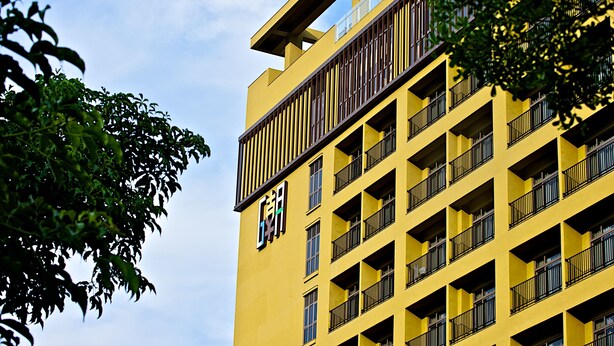 A yellow building with multiple balconies and a visible logo on the side.