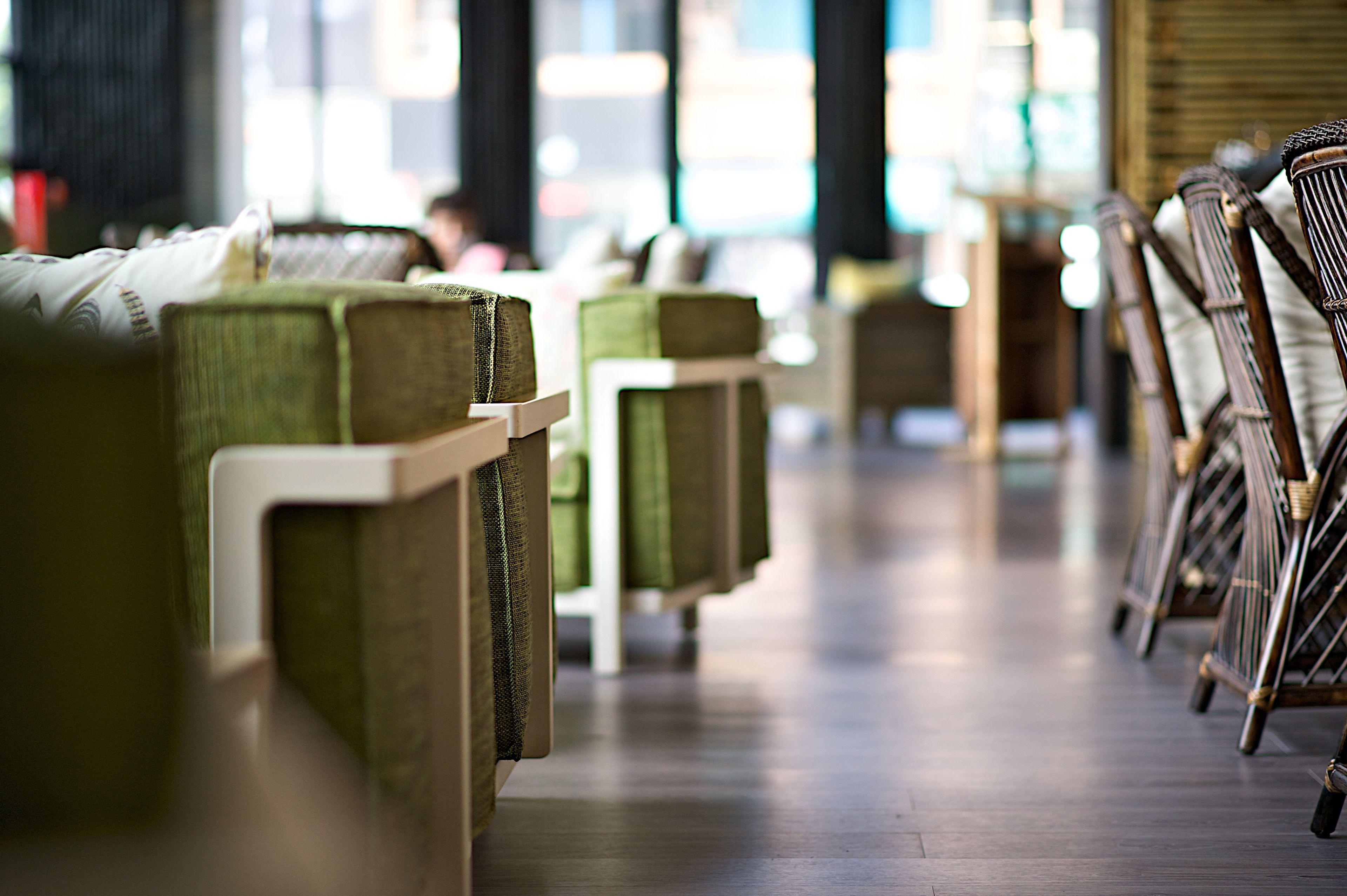 Rows of green upholstered chairs with wooden frames in a spacious indoor area.