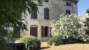 A stone building with arched windows and a tiled roof. - 17th century character house in village center with swimming pool (Saint-Laurent-D'aigouze)
