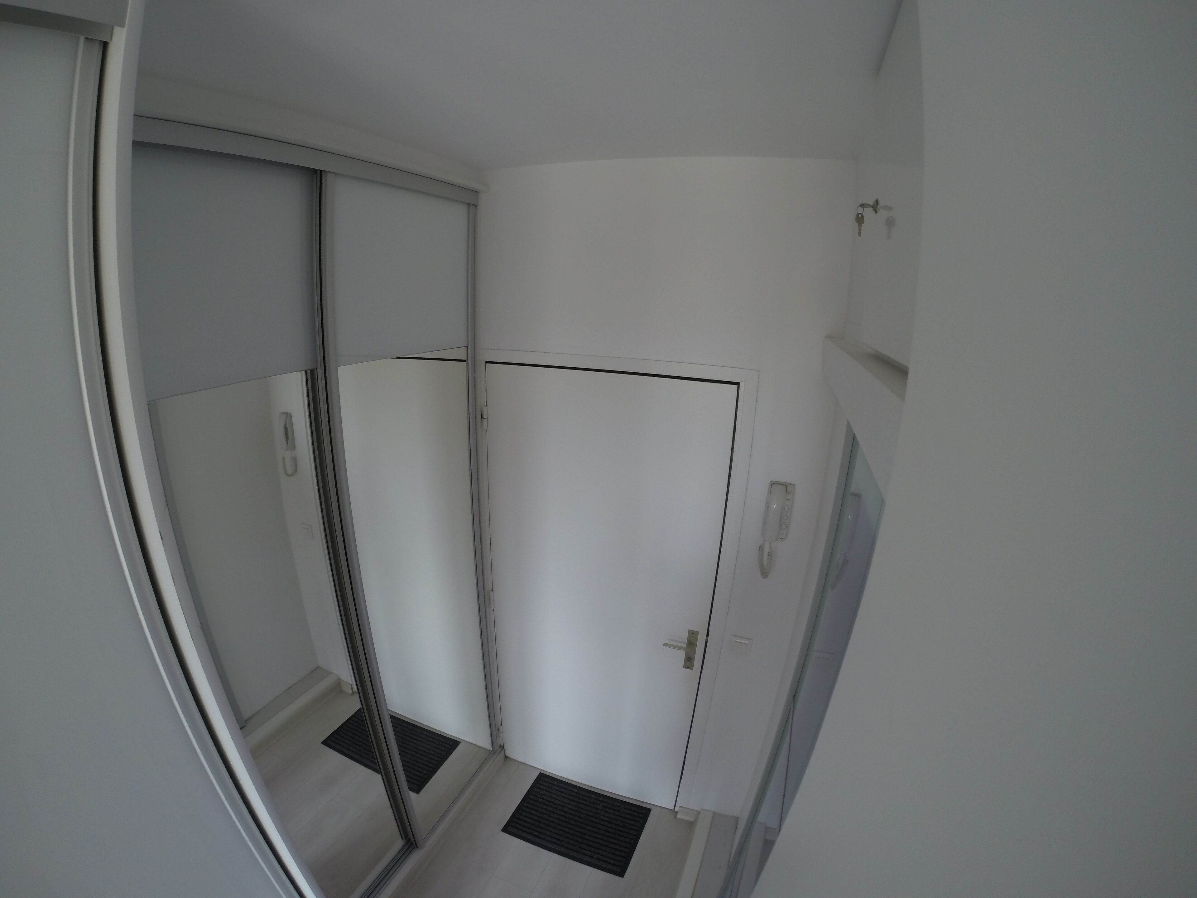 A narrow hallway with a sliding door, a door with a handle, and a wall-mounted telephone.