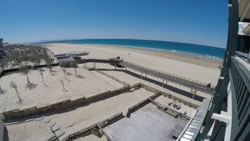 Une vue sur la plage depuis un balcon doté d’une terrasse en bois, avec vue sur la plage et l’océan.