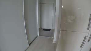 A hallway with a door leading to a room. The hallway has a light-colored floor and walls, and there is a small vent on the wall. - Magnificent ocean view studio (Soorts-Hossegor)
