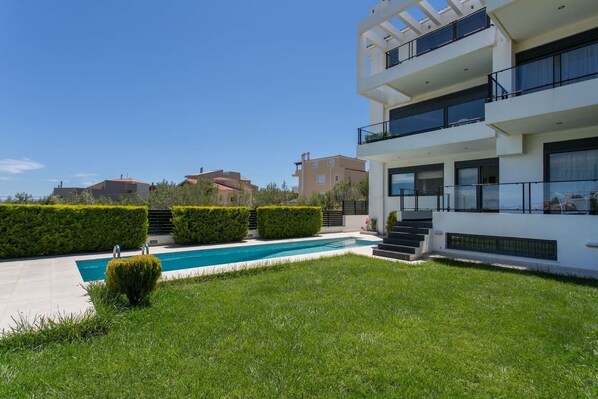 A modern two-story building with a swimming pool, surrounded by well-maintained hedges and grass. - Mountain maissonette in Athens with breathtaking views. (Athens)