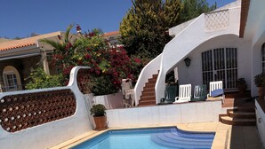 En swimmingpool med ett klart, blått vatten och en vit vägg runt om, dekorerad med ett mönster.
