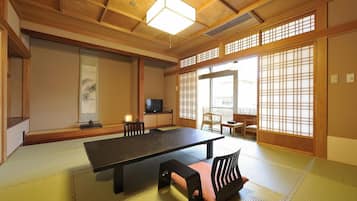 Una habitación japonesa tradicional con suelo de tatami, una mesa baja y puertas correderas.
