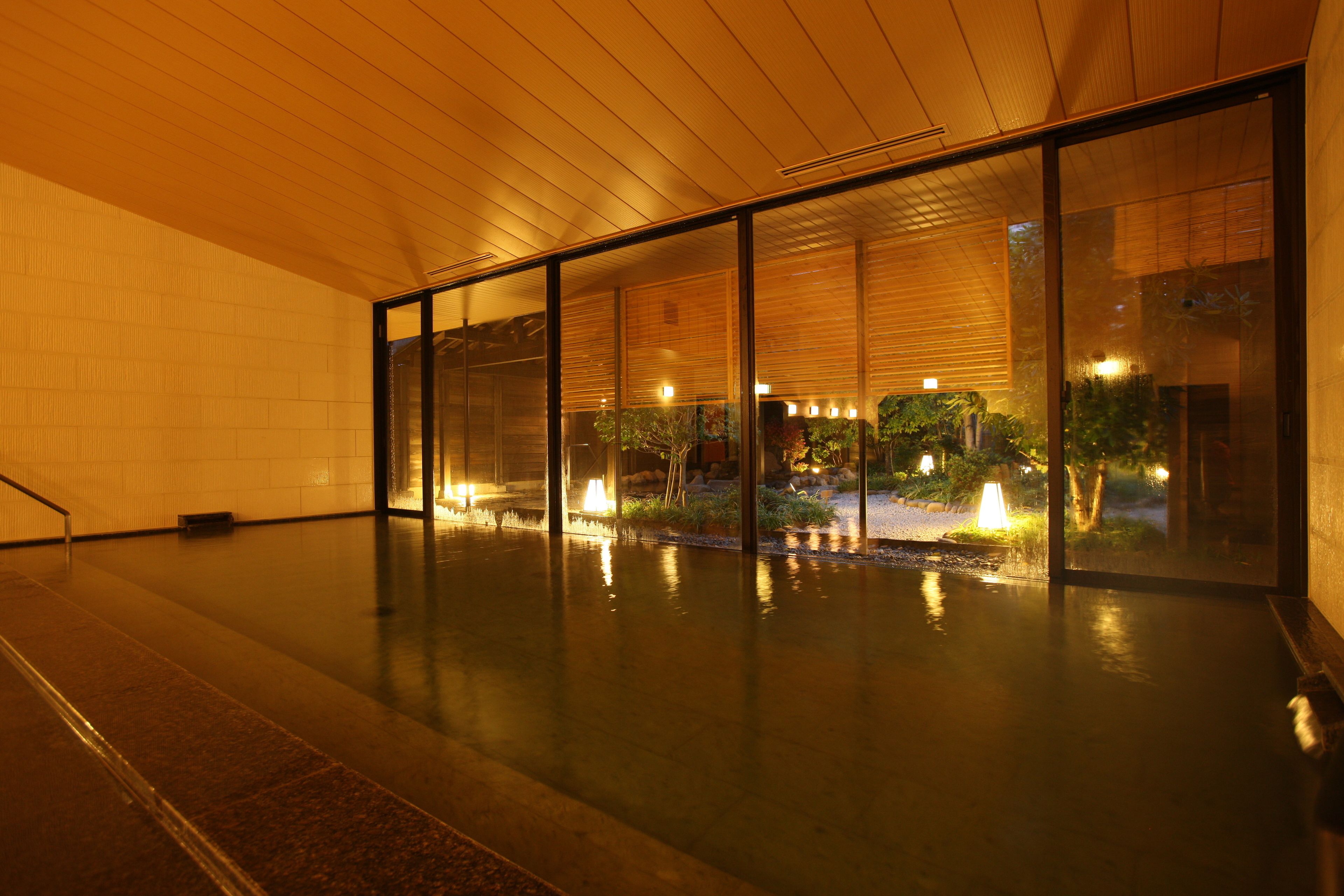 A spacious indoor area with a reflective floor, large windows, and a wooden ceiling.