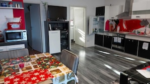 A modern kitchen with a dining area, featuring a microwave, refrigerator, and a flat-screen TV. - Beautiful apartment in Berlin-Mahlsdorf (Berlin)