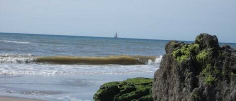 Ein Strand mit einem Felsen und Wellen.