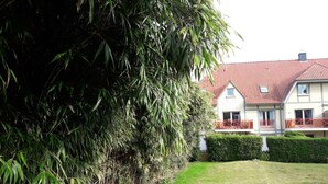 A house with a red-tiled roof, a white exterior, and a red balcony railing. - NEW .. Charming duplex T2 with pool and tennis (Neufchâtel-Hardelot)
