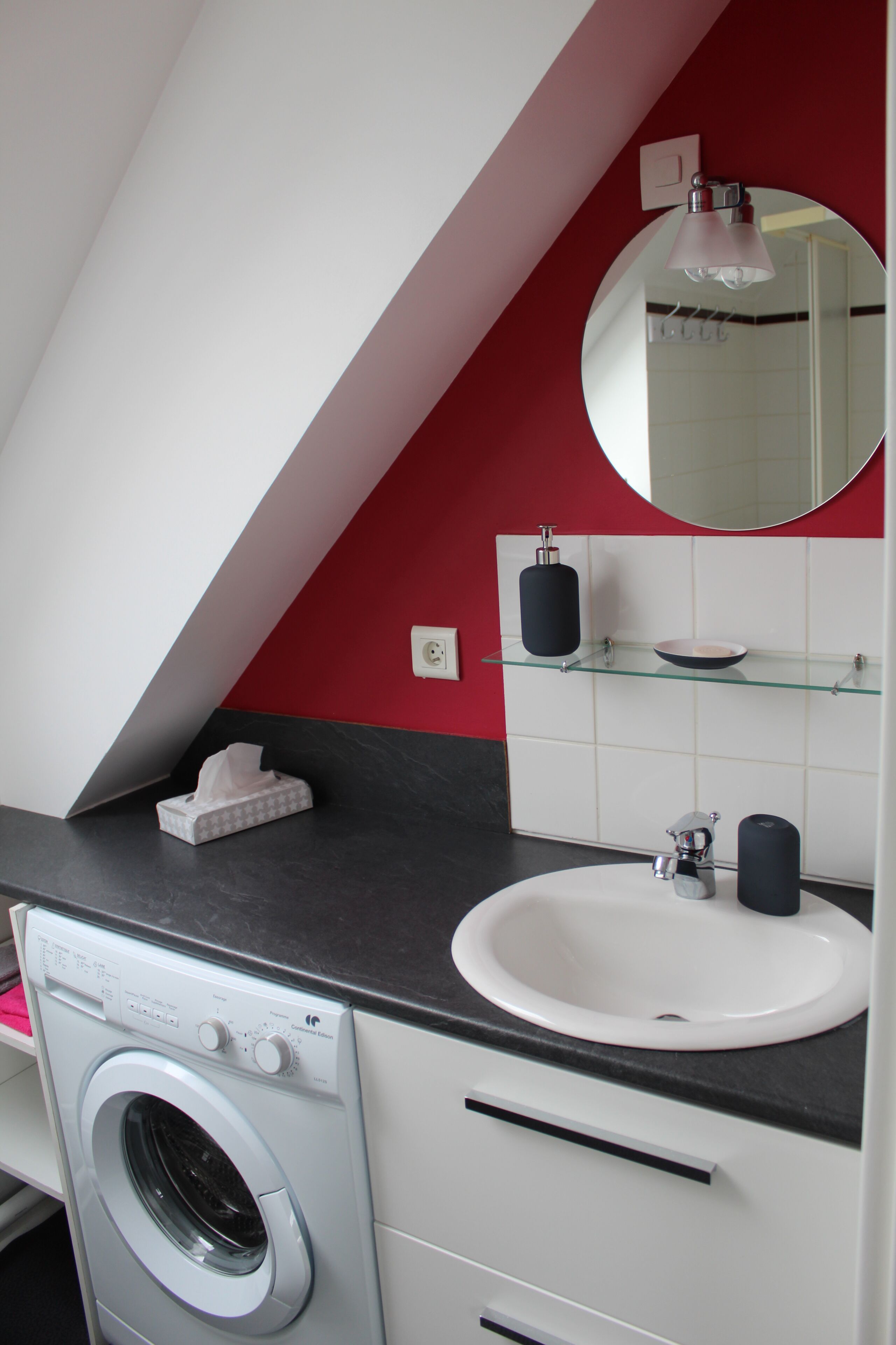 A modern bathroom with a washing machine, a sink, and a mirror.