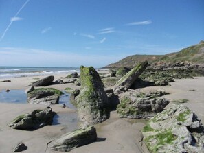 Une plage rocheuse parsemée de gros blocs et un ciel dégagé.