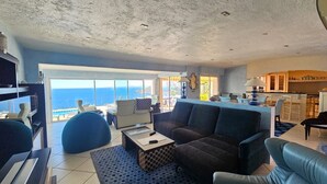 Un amplio salón con un sofá grande, una mesa de centro y vistas al océano.