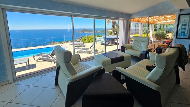 Un balcón amplio con vistas al mar, una piscina y mobiliario de exterior.