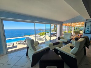 Un balcó ampli amb vista al mar, una piscina i mobiliari exterior.