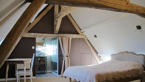 Une chambre avec un plafond en pente, un lit en bois, une chaise et un petit bureau.