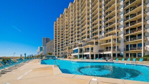 A hotel with a pool area, multiple balconies, and a view of the city skyline.