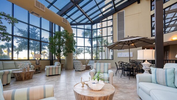 A spacious indoor area with large windows, comfortable seating, and a central round table.