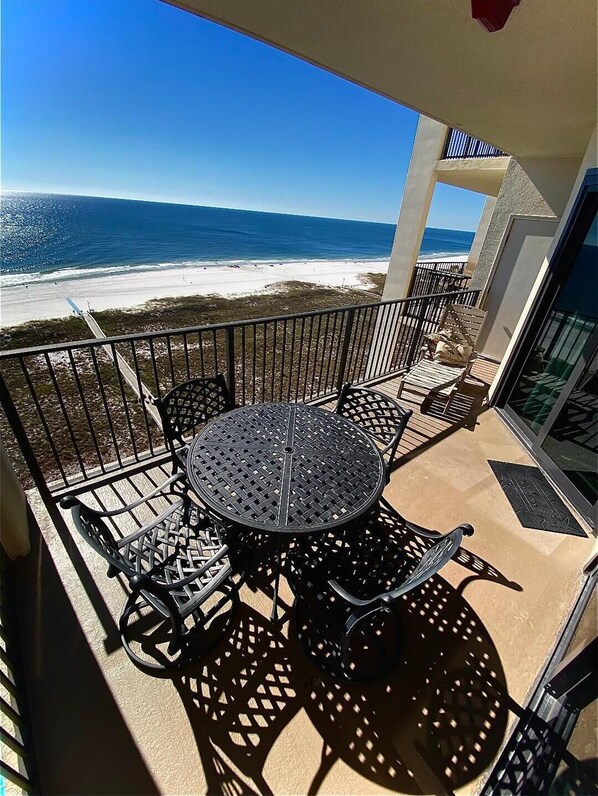 A balcony with a round table and chairs, overlooking a beach with white sand and the ocean. - Garage Parking included! BEACHFRONT CONDO with A GULF Front MASTER! AWESOME VIEW (Orange Beach)