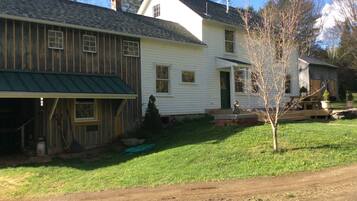 A two-story house with a green metal roof, a front porch, and a small front yard.