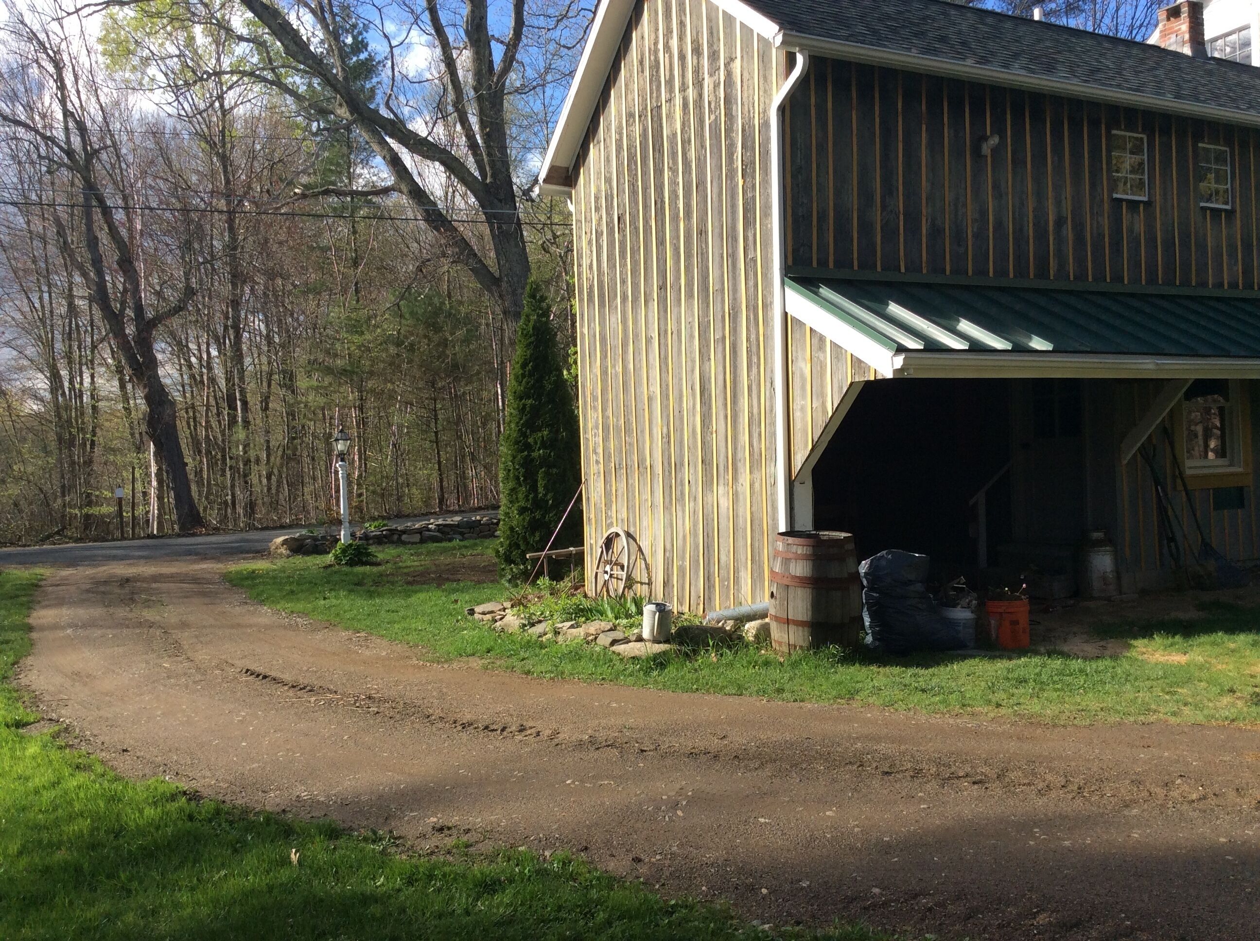 A wooden barn with a green roof and a garage.