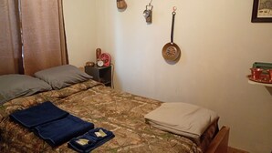A bedroom with a bed, pillows, a bedside table with a clock, and a hanging pot. - Only 1 dollar cleaning fee at Pictured Rocks Basecamp on the Manistique River! (Germfask)