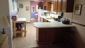 A kitchen with wooden cabinets, a white countertop, and a small island with stools.
