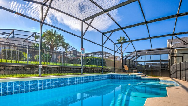 An indoor swimming pool with clear blue water, surrounded by a metal frame structure and glass panels. - Orlando Comfort, Splash and FUN in Windsor Palms Resort - Disney next door (Kissimmee)