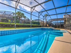 Une piscine intérieure à l’eau d’un bleu limpide, entourée d’une structure en métal et de panneaux de verre.