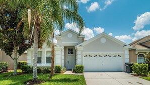A single-story house with a white garage door, a front door, and a small porch. - Orlando Comfort, Splash and FUN in Windsor Palms Resort - Disney next door (Kissimmee)