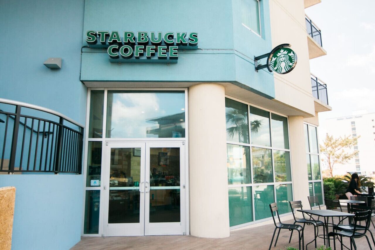 Een Starbucks Coffee winkel met grote glazen deuren, terras en een zichtbaar balkon.