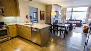 A modern kitchen with wooden cabinets, a central island, and a dining area with a table and chairs. - Luxury Westin Resort and Spa Ski-in/out, sleeps 8, Mountain Views (Avon)