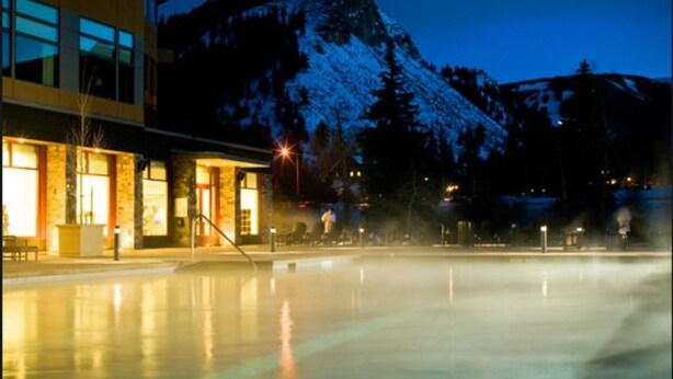 A spa area with a hot tub, a building with large windows, and a mountain in the background. - Luxury Westin Resort and Spa Ski-in/out, sleeps 8, Mountain Views (Avon)