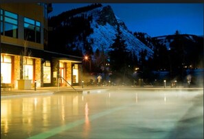 A spa area with a hot tub, a building with large windows, and a mountain in the background.