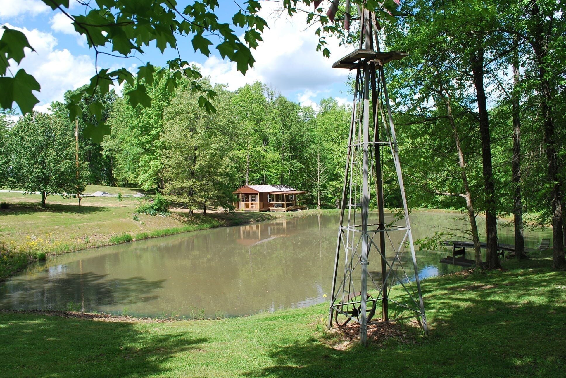 A cabin by a pond surrounded by trees.