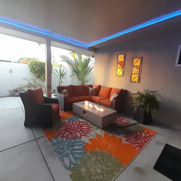 A modern outdoor seating area with a sofa, chairs, and a fire pit.