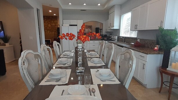 A dining room with a long table set for six, surrounded by chairs. There is a kitchen area with white cabinets and a countertop visible to the right. - Luxe 6Bd/6Ba,5 Minutes Disney Convention C, Beaches 20minutes


















 (Anaheim)